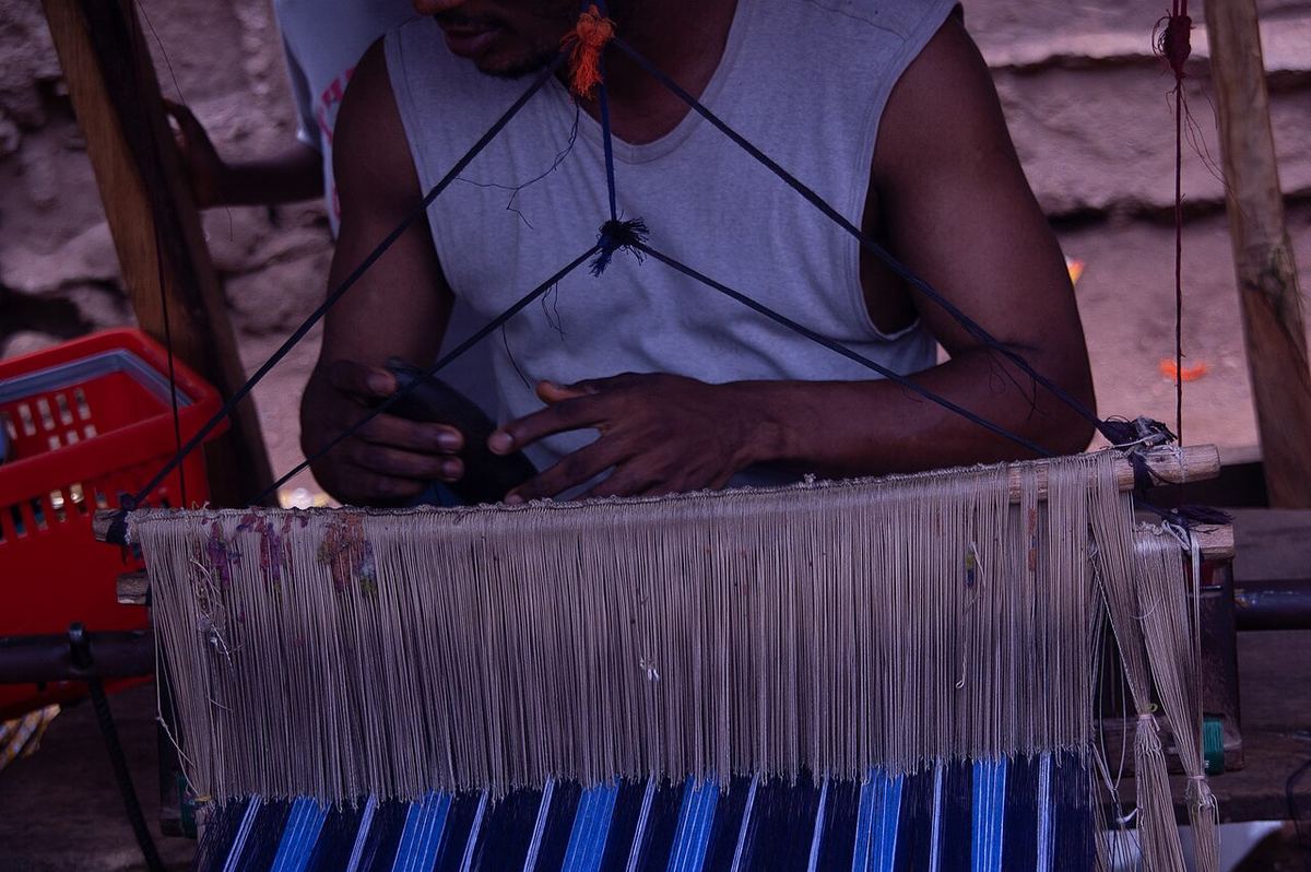 Weaver working a narrow strip loom with colourful threads