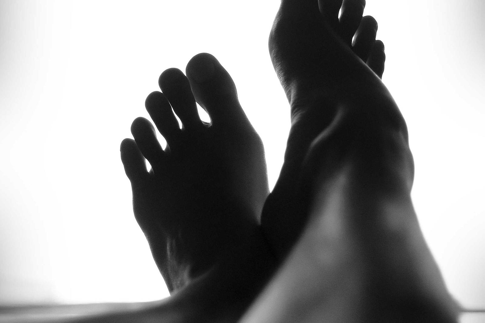 Backlit silhouette figure in black and white, forearms raised across the face like a studio study