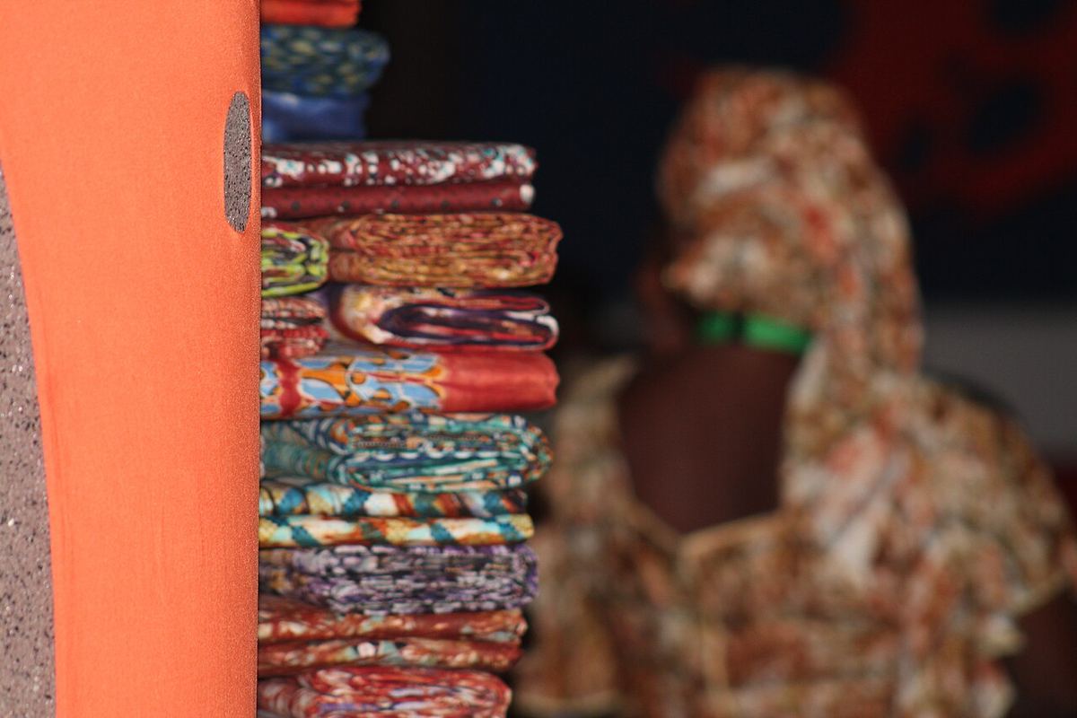 Portrait of a woman selling adire fabric at a market table